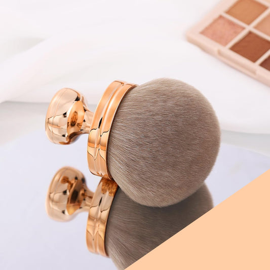 Wide-Head Foundation & Bronzer Brush on a reflective surface with a soft, round brush head.